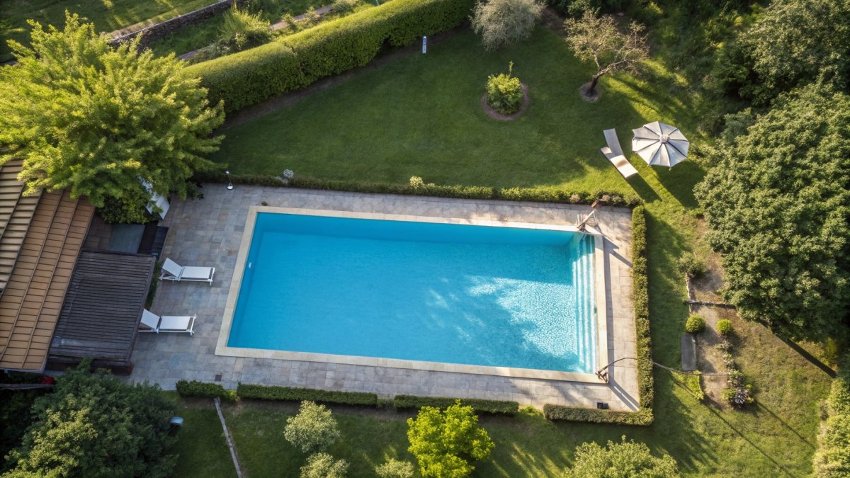 Piscine rectangulaire entourée de pelouse et arbres, vue aérienne d'un jardin paysagé